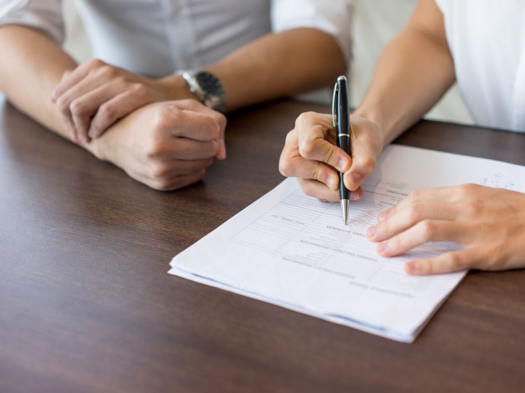 Photo des mains de deux personnes complètant un document